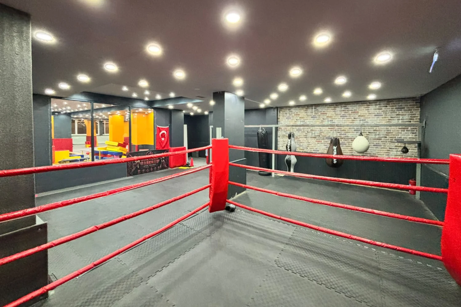 Göktürk şubesi salonu: ring, kum torbaları ve cam arkasında çocuk alanı